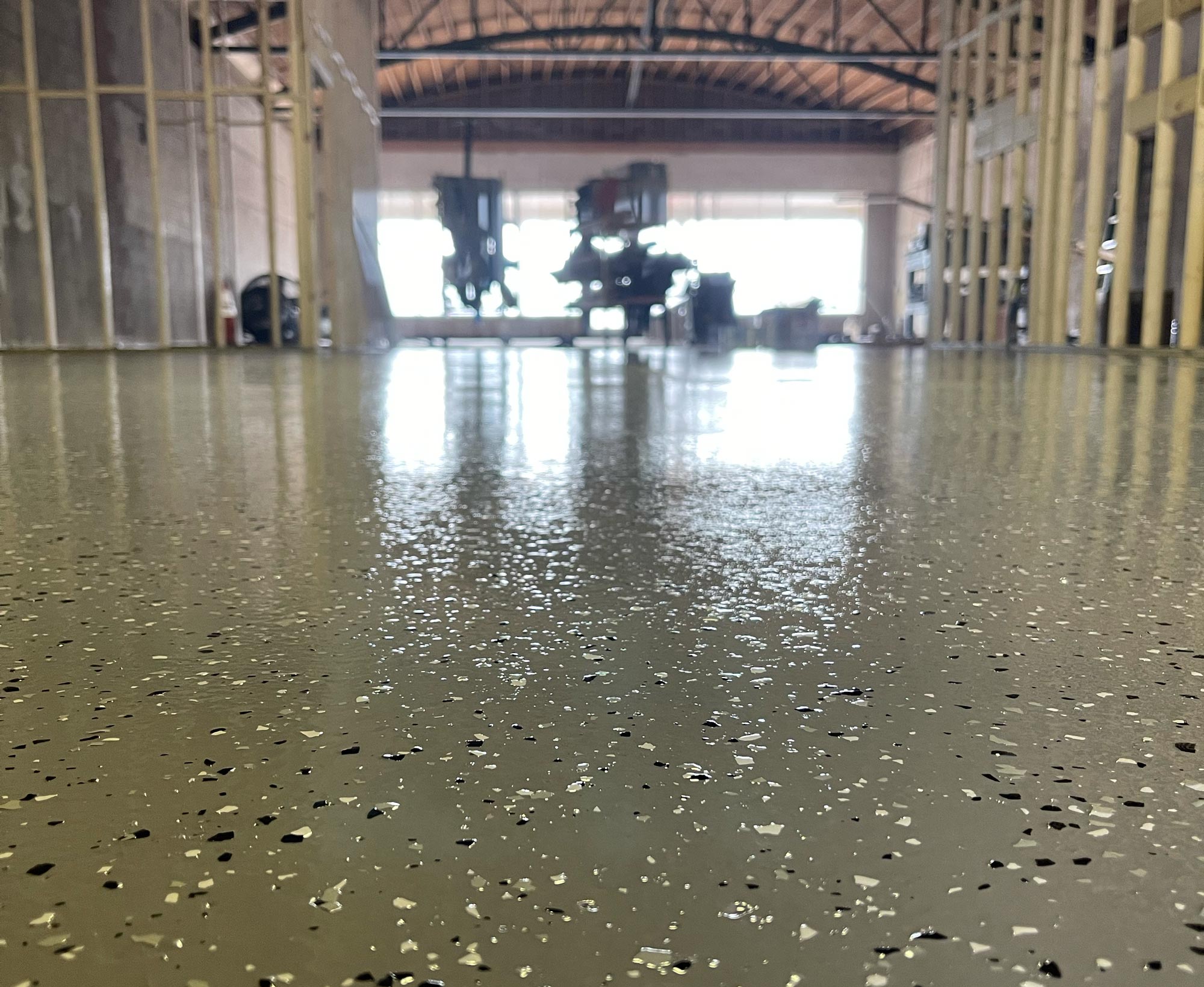 Close-up of a shiny, speckled concrete floor in a building under construction with wooden framing.